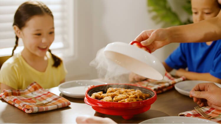 Family at a kitchen table being served food from the Rocket Chef Turbo Grill